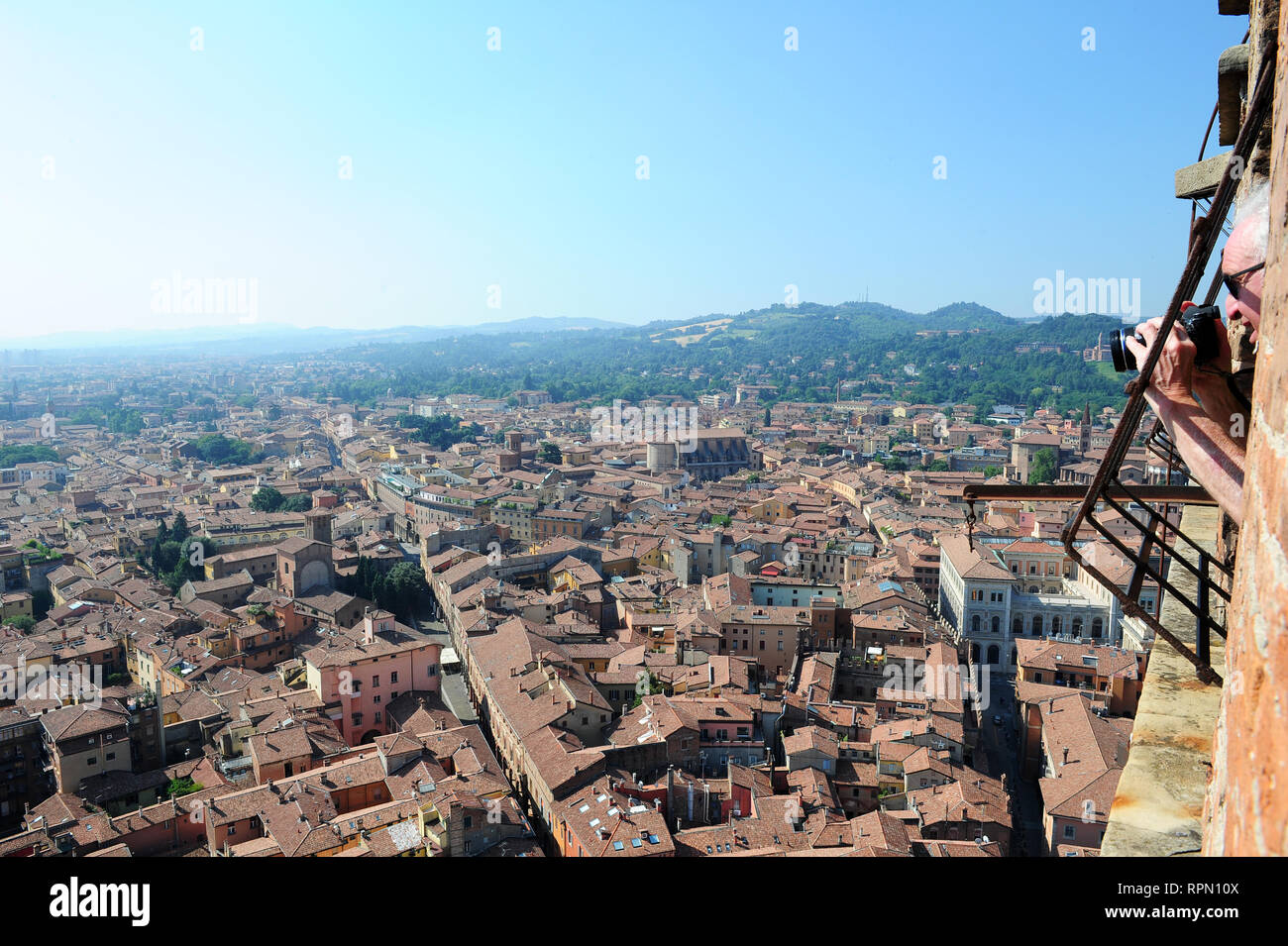 Ein Mann lehnte sich aus einem der Fenster auf der Oberseite der Asinelli Turm in Bologna ein Bild von der Stadt unter Stockfoto
