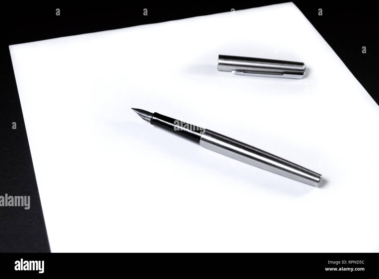 Auf einem weißen Blatt Papier ist ein Kugelschreiber mit einer Kappe.  Schwarzer Hintergrund Stockfotografie - Alamy