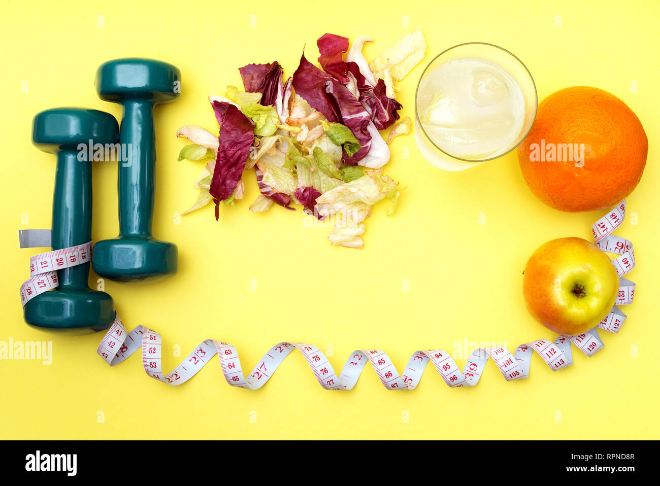 Hanteln für Sport. Fitness Salat und Maßband auf einem gelben Tabelle. Orangen, Äpfel und klares Wasser mit Eis für das Konzept einer gesunden lifestyl Stockfoto