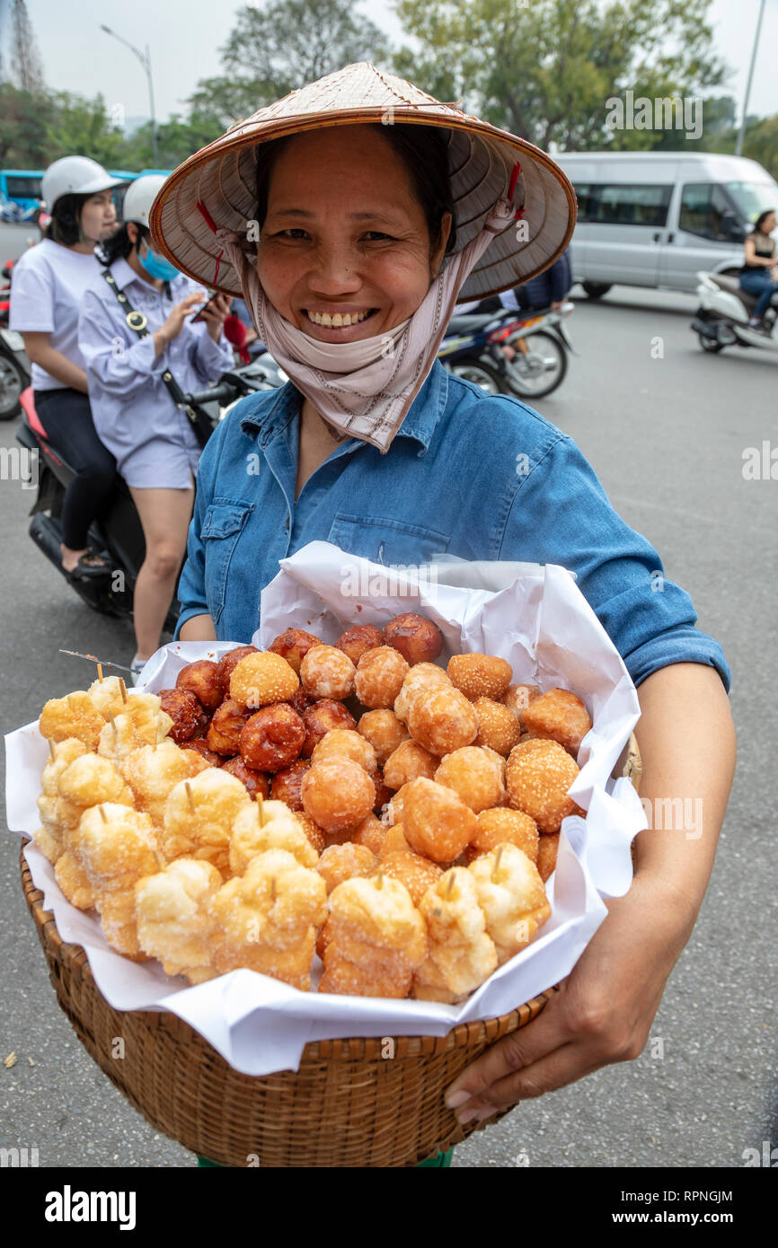 Frau Verkauf von Gebäck und frittierte Gemüse aus einem Weidenkorb auf der Street, Hanoi, Vietnam, Asien Stockfoto
