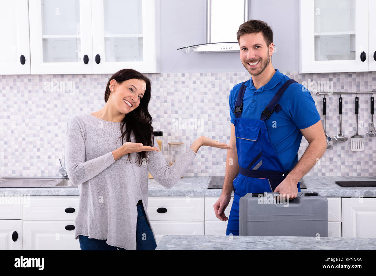 Porträt der jungen Frau die männlichen Reparateur in der Küche Stockfoto