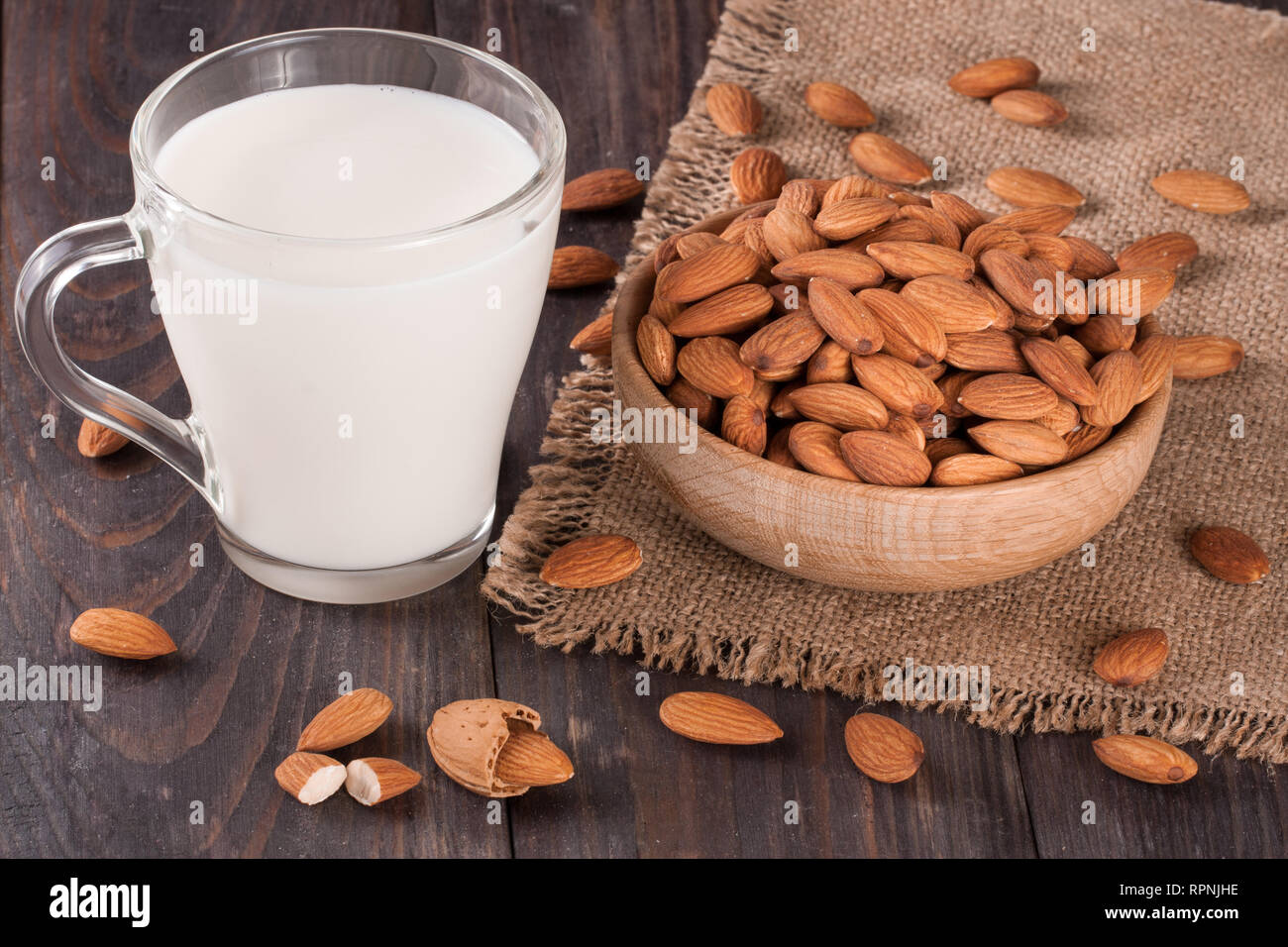 Mandel Milch in ein Glas und Mandeln in einer Schüssel auf dunklem Hintergrund Stockfoto