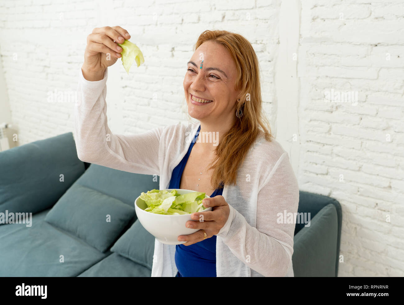 Fröhliche Frau, Schüssel grünem Salat Gefühl glücklich zu ändern auf grauem Hintergrund in neuen Lifestyle Ayurveda Ernährung Ernährung isoliert Stockfoto