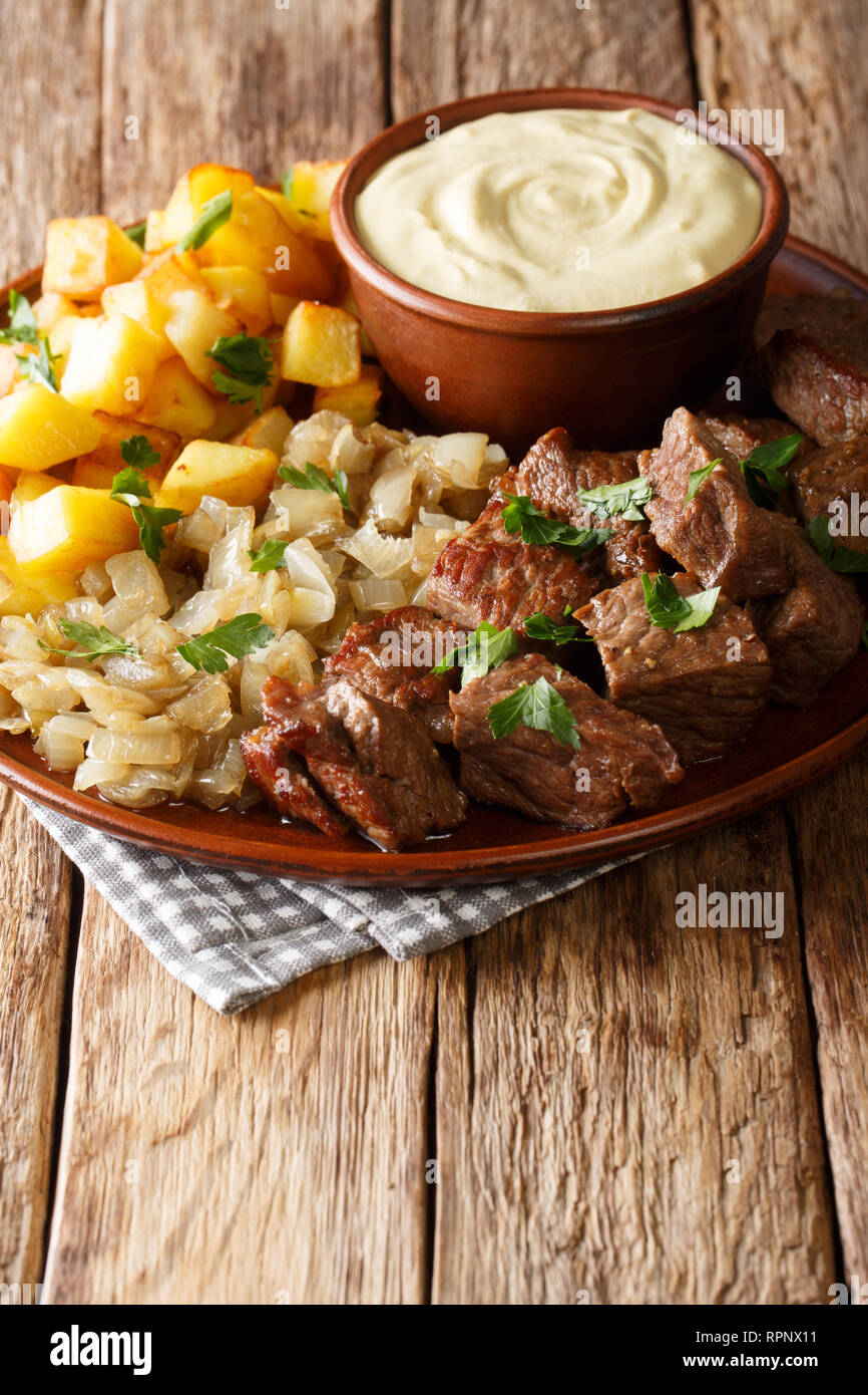 Schwedische Rezept pyttipanna für Rindfleisch rydberg mit geschmorten Zwiebeln und Bratkartoffeln mit Senfsauce close-up auf einem Teller auf den Tisch. Vertikale Stockfoto