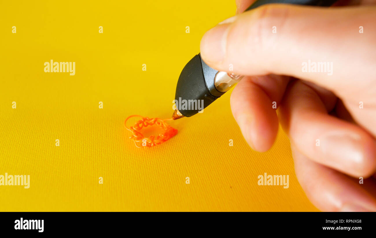Die Hand eines Mannes zieht mit einem 3D-Drucker pen auf gelbem Hintergrund, Filmmaterial ideal für Themen wie Innovation, Technologie Stockfoto