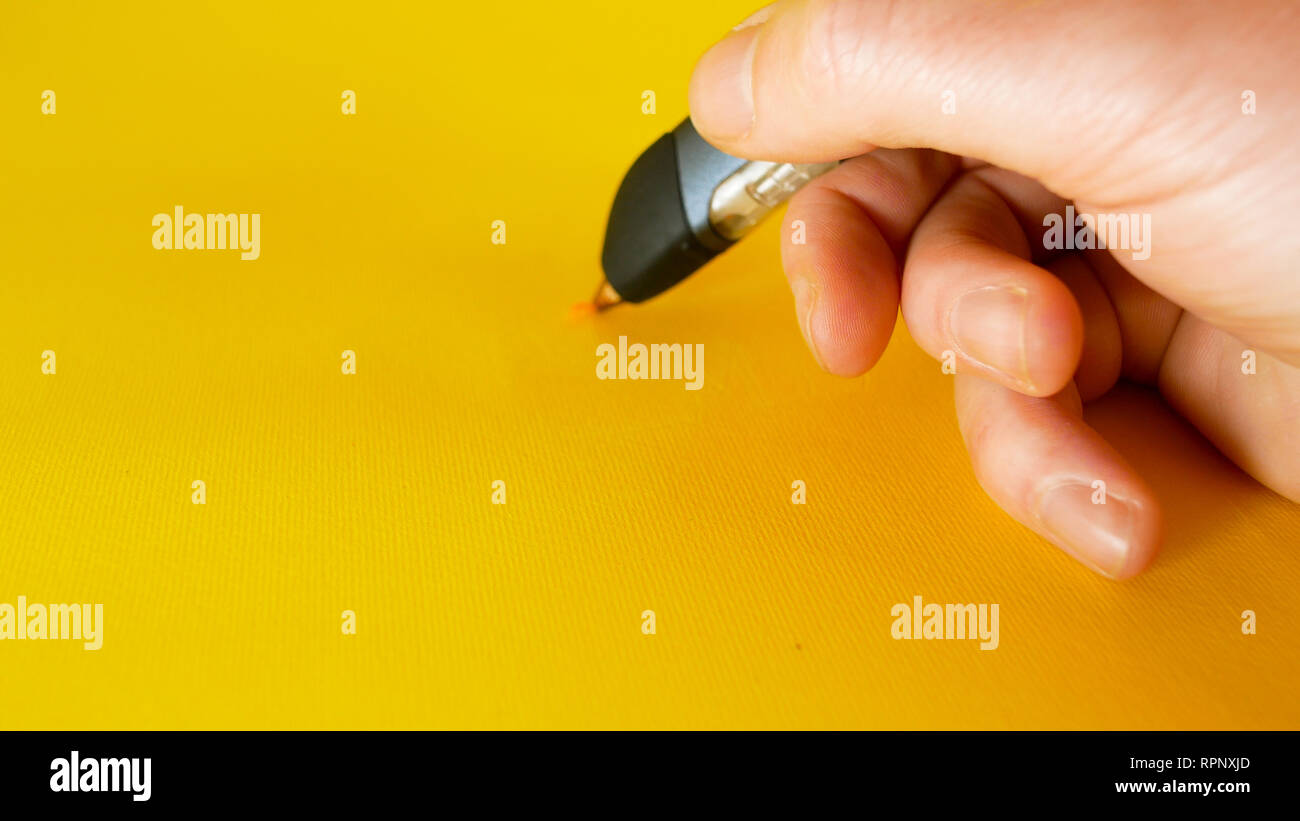 Die Hand eines Mannes zieht mit einem 3D-Drucker pen auf gelbem Hintergrund, Filmmaterial ideal für Themen wie Innovation, Technologie Stockfoto