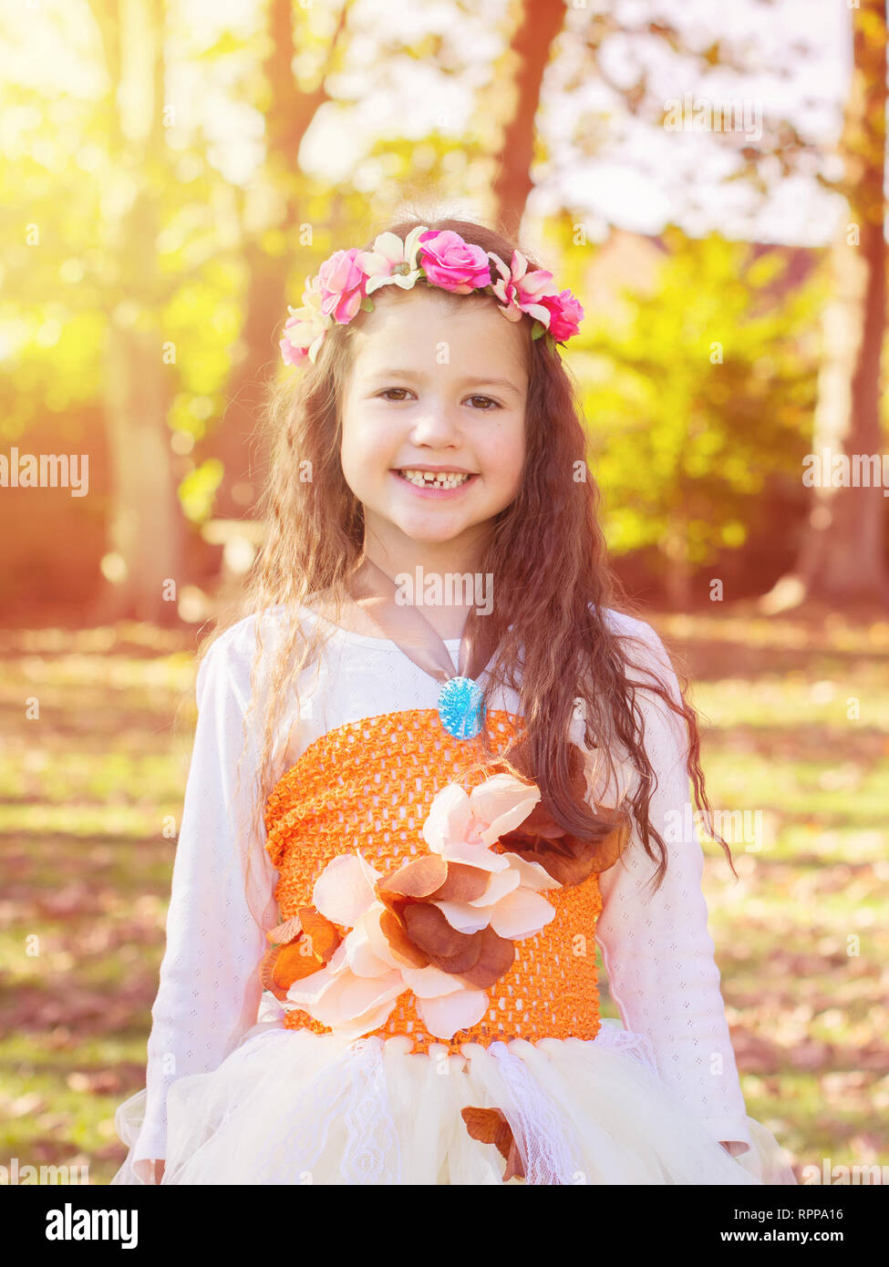 Kleines Mädchen im Garten gegen die Sonne in Tutu Kleid und Blume Stirnband, getönt, selektiven Fokus Stockfoto