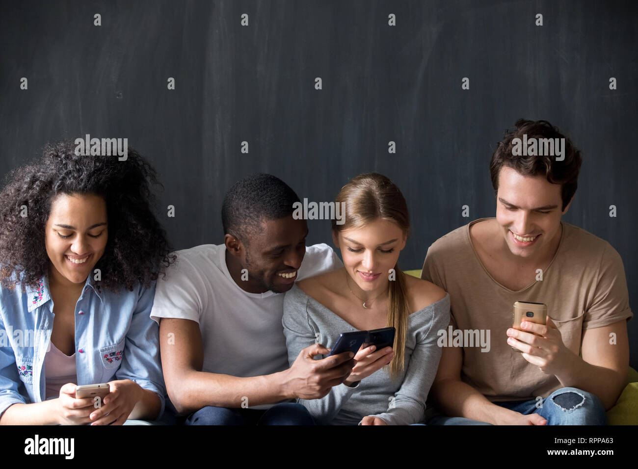 Lächelnd multirassischen Freunden über Telefone zusammen, die gemeinsame Nutzung von Nachrichten Stockfoto