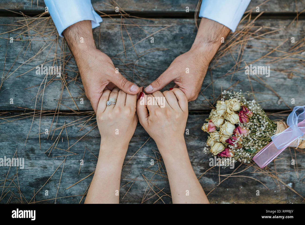Hochzeit Paar, Hände auf Holztisch mit Blumenstrauß Stockfoto