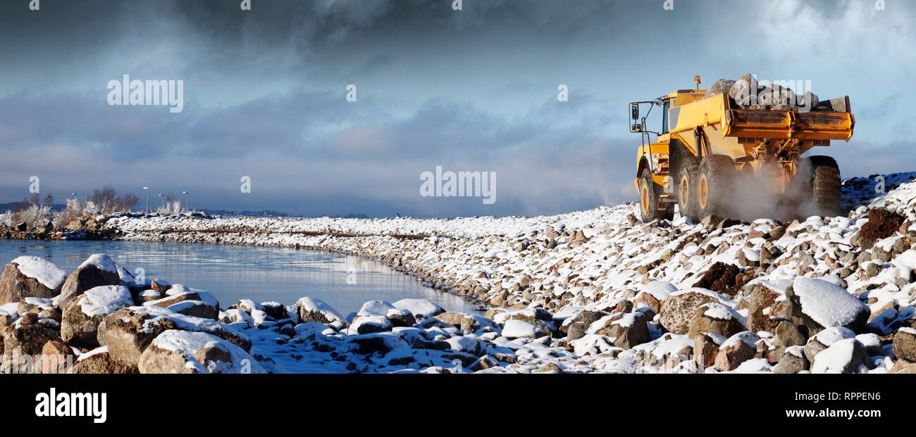 Muldenkipper Bewegen von großen Felsen aus dem Meer - Bett im Winter. Stockfoto
