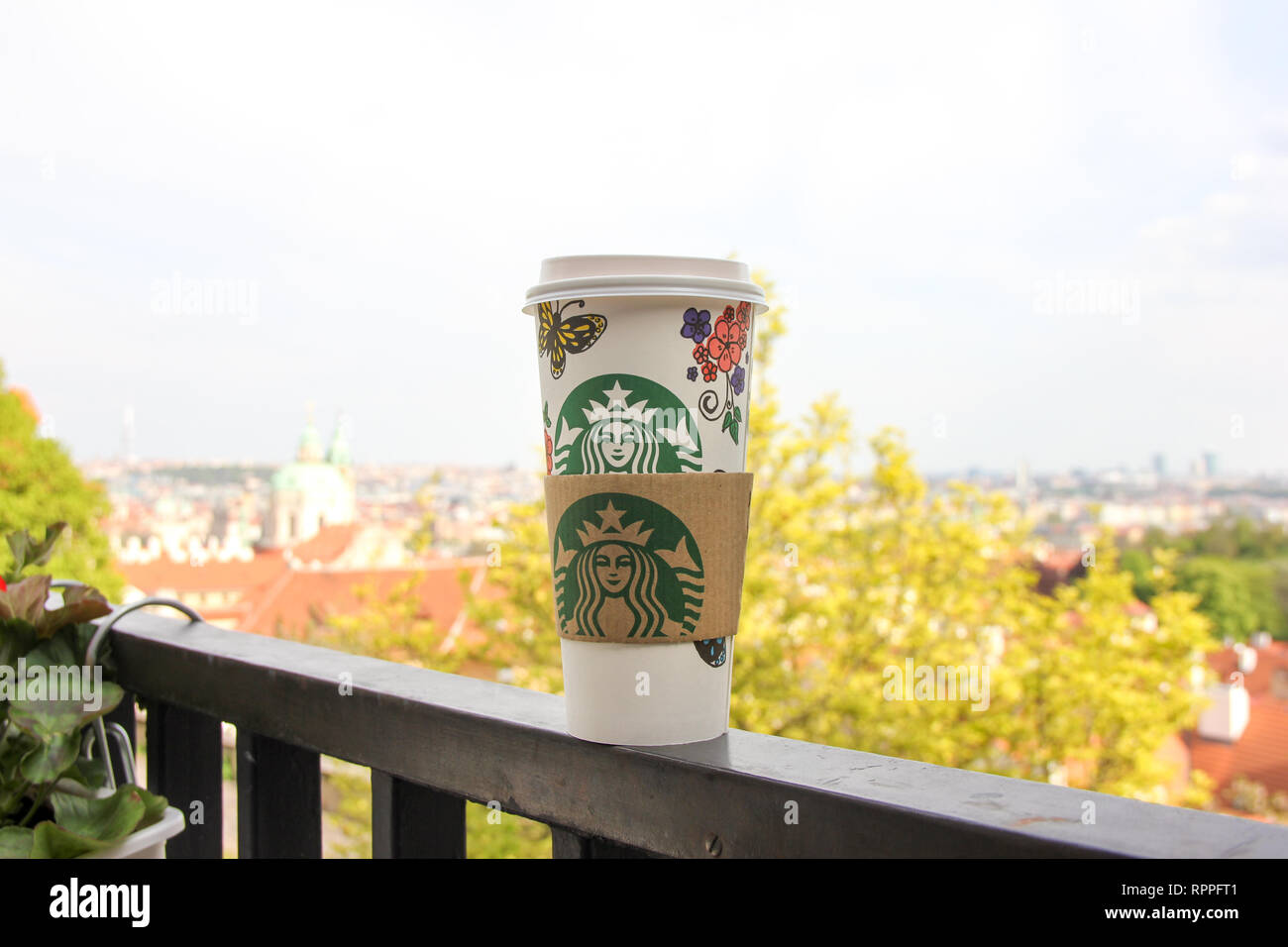 Helle Stadt Ansicht mit Starbucks Papier Tasse Kaffee steht auf dem Balkon Geländer im Vordergrund. Schönen goldenen Herbst Baum Stockfoto