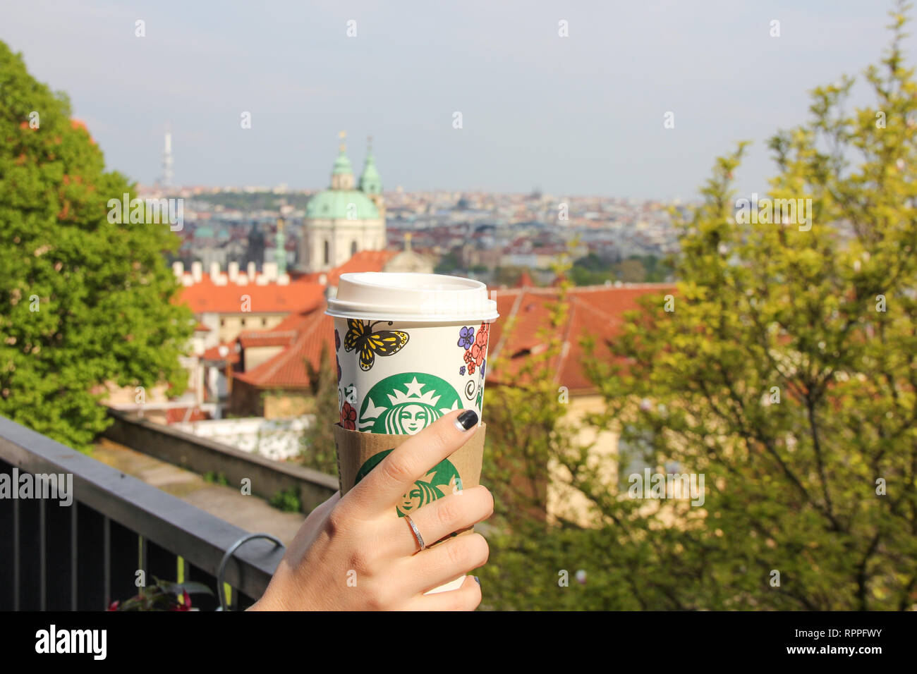 Helle Stadt Ansicht mit Starbucks Papier Tasse Kaffee steht auf dem Balkon Geländer im Vordergrund. Schönen goldenen Herbst Baum Stockfoto