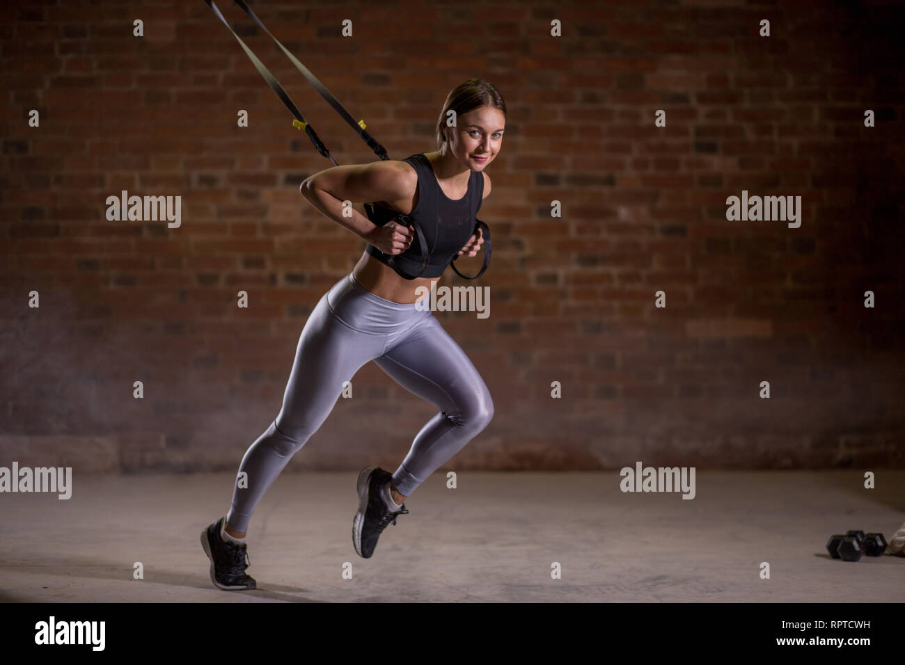 Fitness Frau trainin am TRX in der Turnhalle, Sprinter Übung starten, wo Muskeln stabilisieren ausgebildet sind und der ganze Körper arbeitet, die Stockfoto