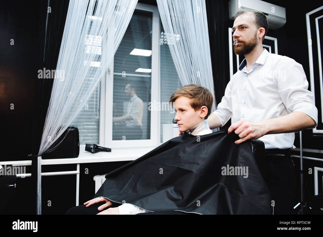 Junge schöne Friseur die Haare schneiden von süßen Jungen im barbershop Stockfoto