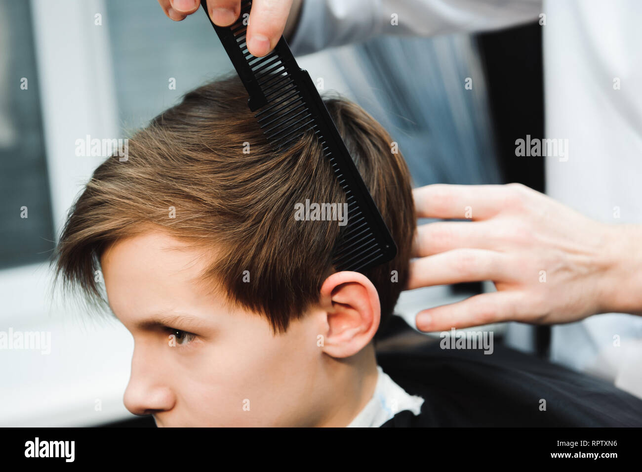 Junge schöne Friseur die Haare schneiden von süßen Jungen im barbershop. Stockfoto