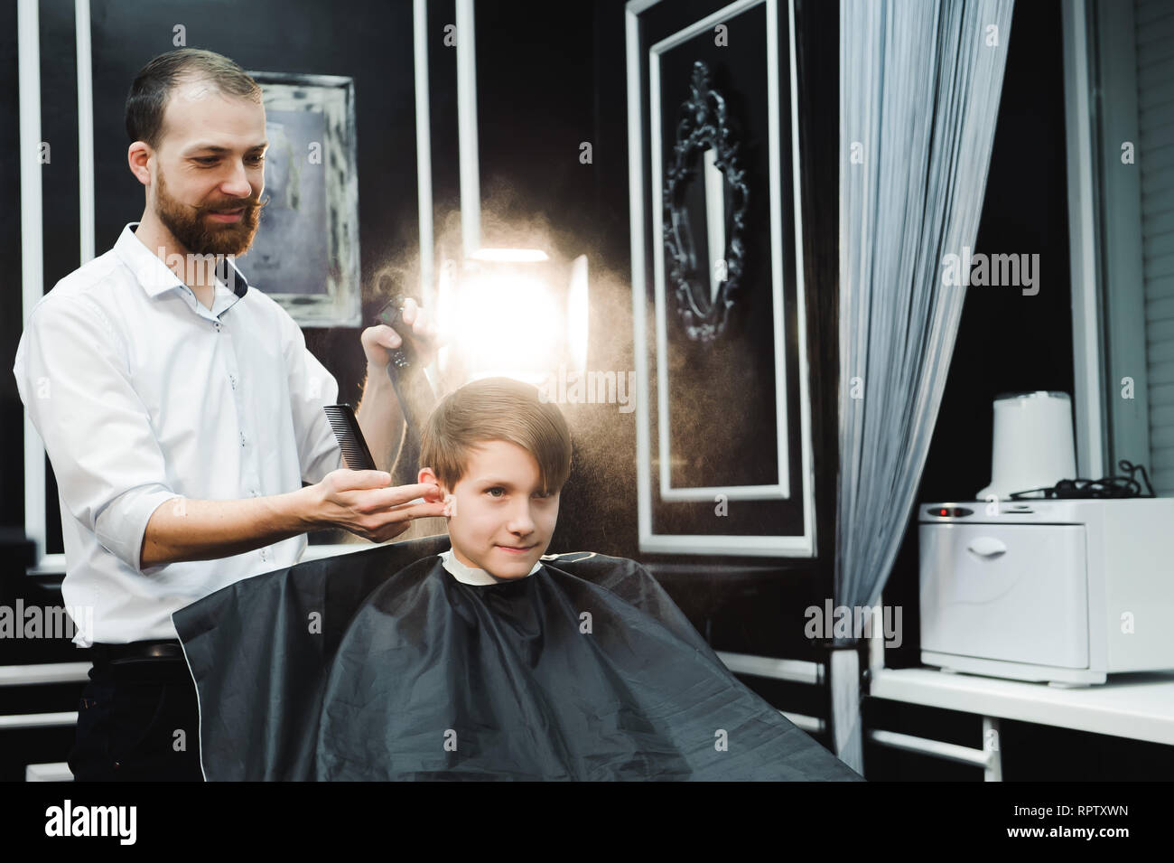 Junge schöne Friseur die Haare schneiden von süßen Jungen im barbershop. Stockfoto