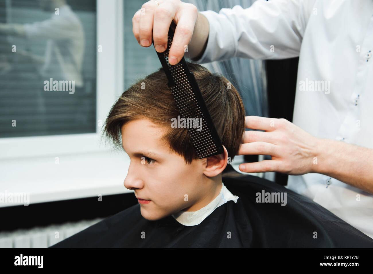 Junge schöne Friseur die Haare schneiden von süßen Jungen im barbershop Stockfoto