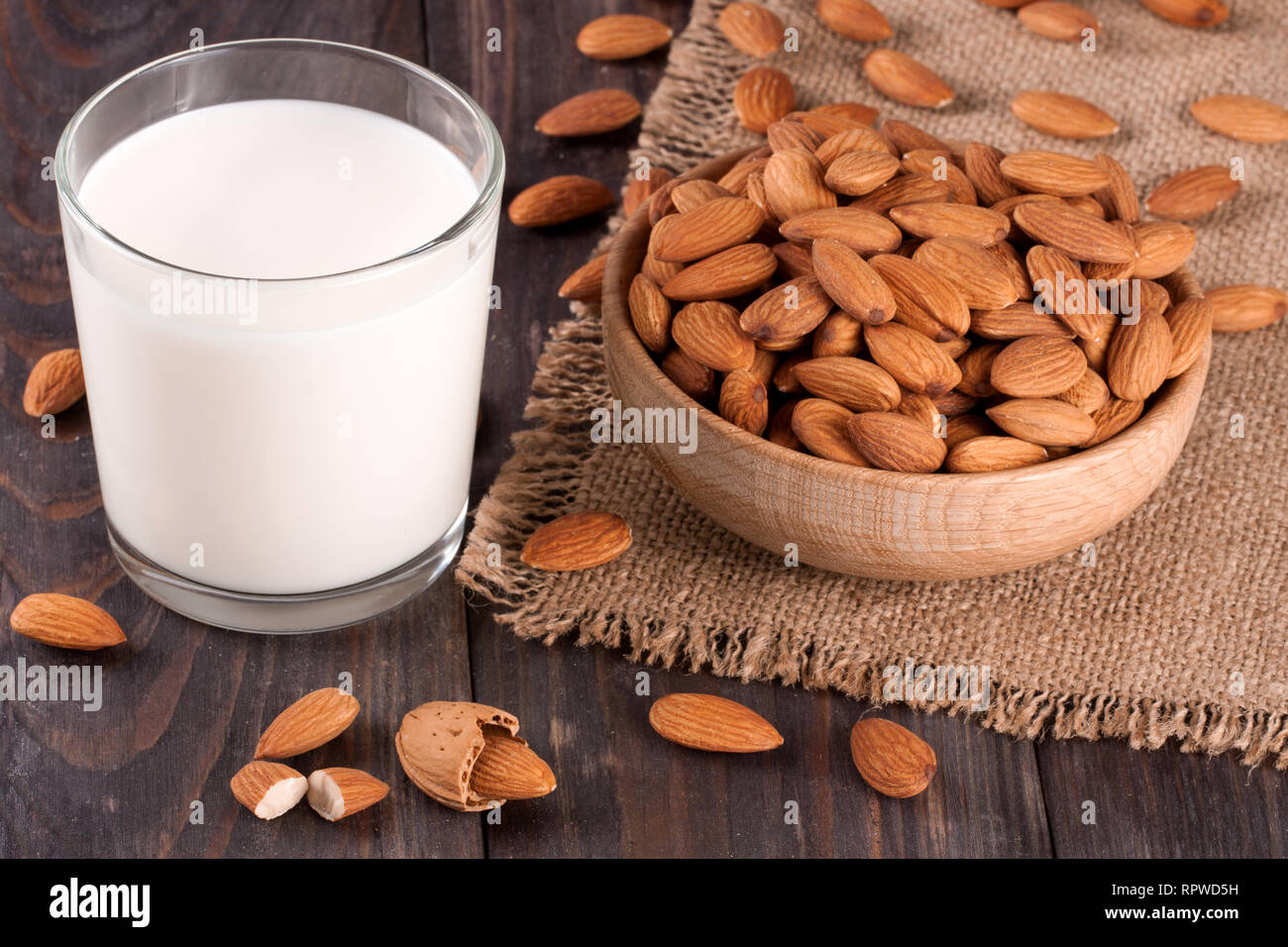 Mandel Milch in ein Glas und Mandeln in einer Schüssel auf dunklem Hintergrund Stockfoto