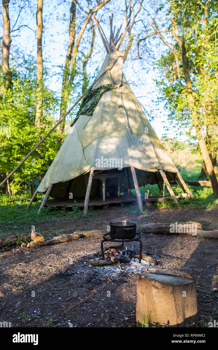 Kochen über einem Lagerfeuer durch ein Tipi in einem Waldgebiet in Kent, Großbritannien Stockfoto