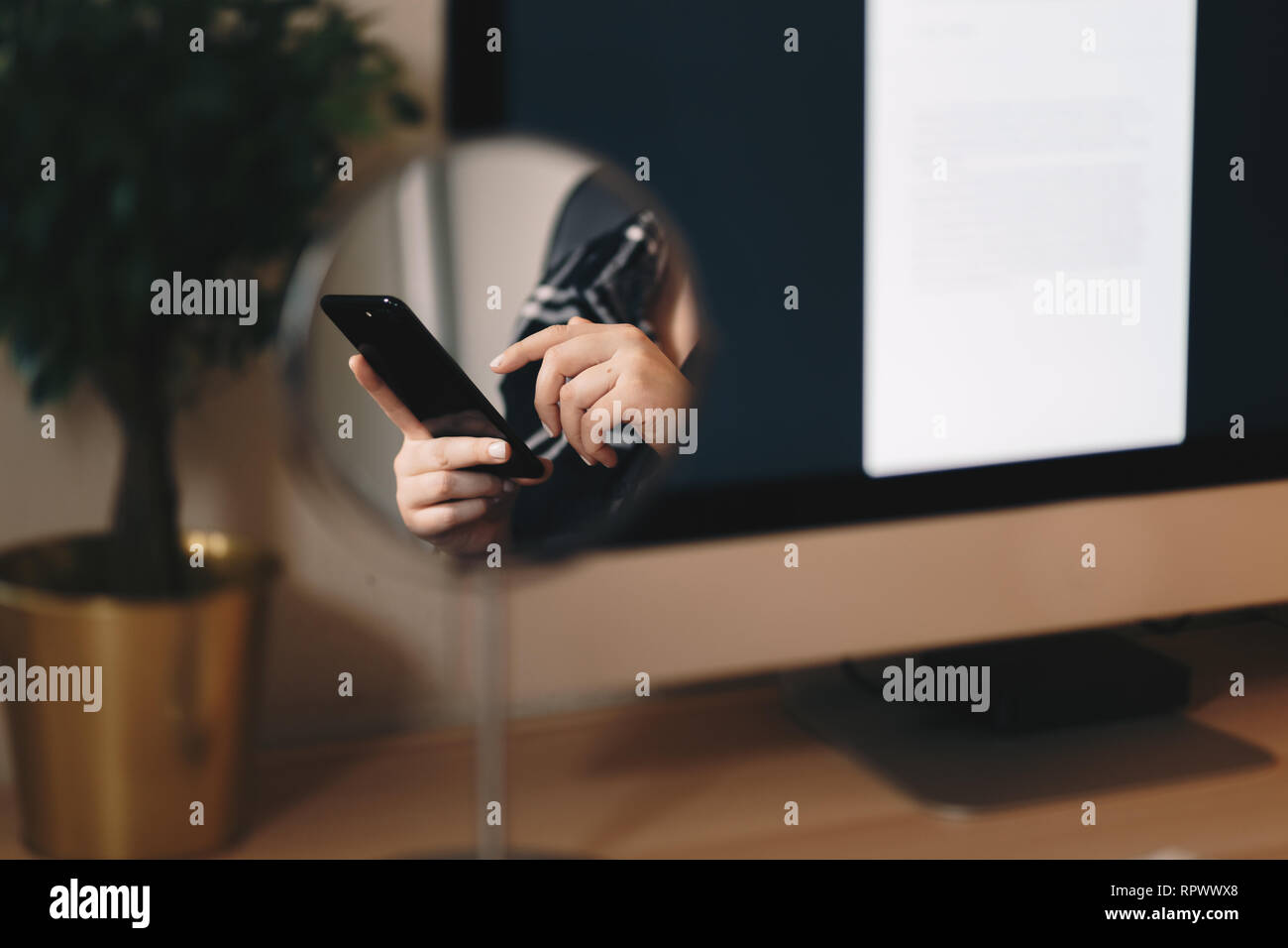 Detail Schuß einer Reflexion der Frau Hände in einem Kosmetikspiegel, Tippen auf ein smart phone im Home Office wie Raum. Stockfoto