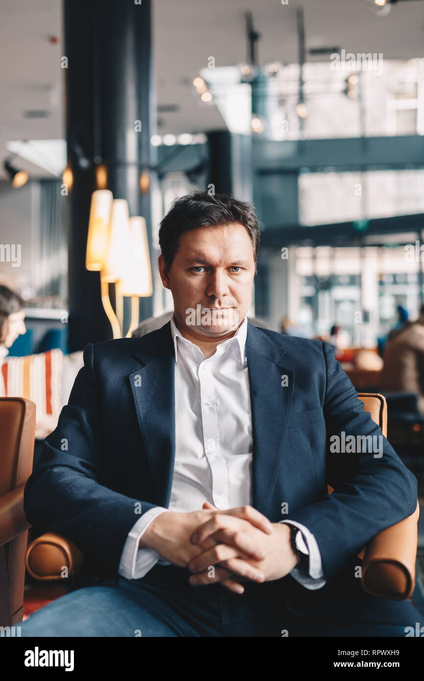 Close-up Portrait von gut aussehende junge Unternehmer mit hohem Selbstwertgefühl, sitzen in einer Bar, posieren für die Kamera. Bild vertikal mit Platz für Text Stockfoto