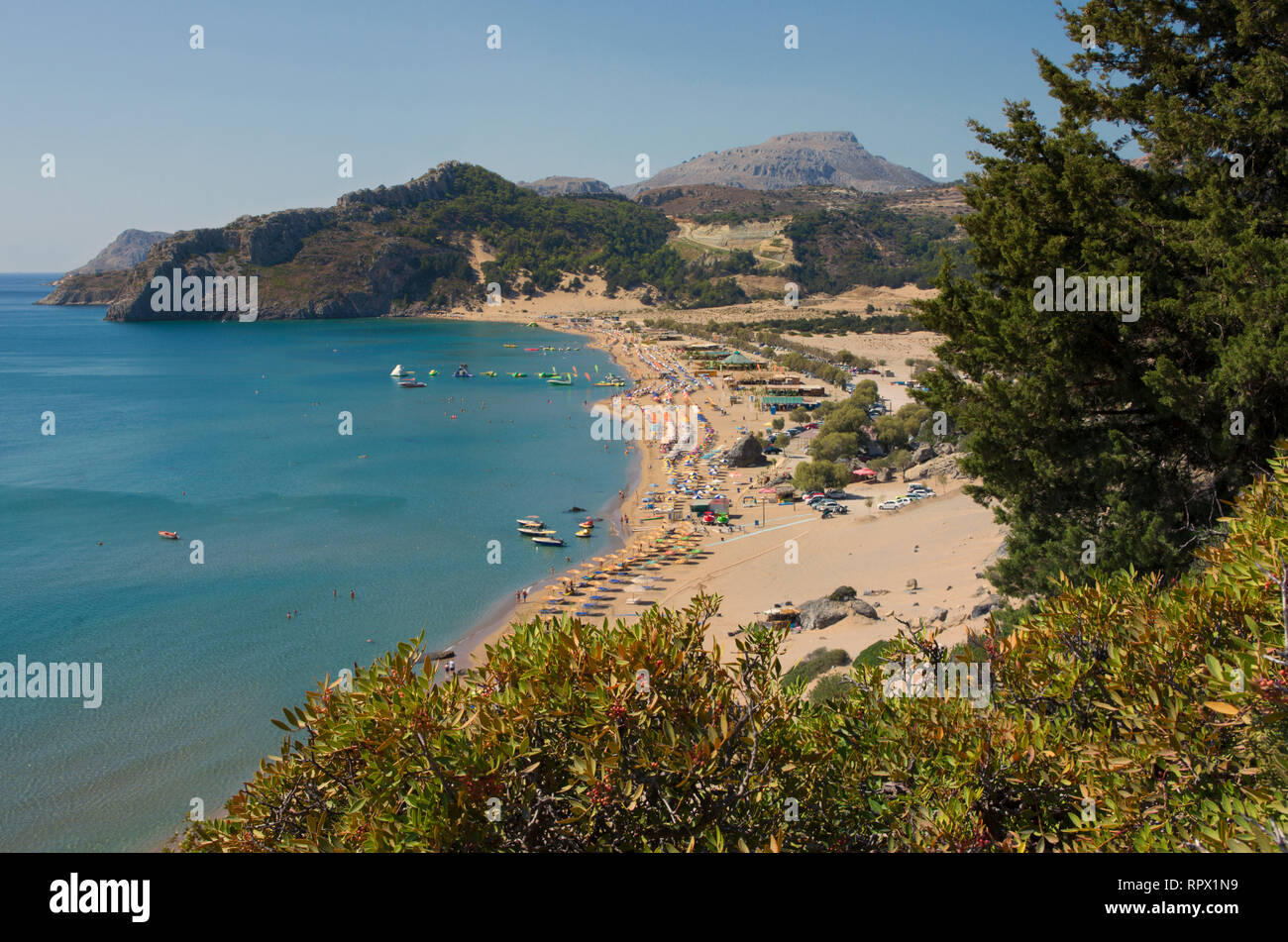 Griechische Strand Tsampika mit azurblauem Wasser an einem wolkenlosen Sommertag mit vielen Liegen und Sonnenschirmen (Rhodos, Griechenland) Stockfoto