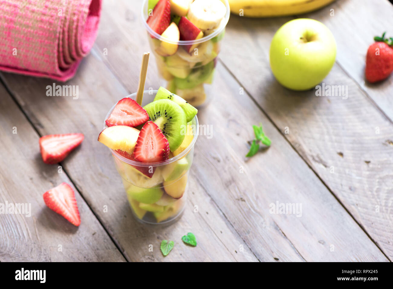 Sport und eine gesunde Lebensweise. Rosa Yoga Matte und Obst und Beeren Salat in Schale aus Kunststoff zu gehen, Platz kopieren, Ansicht von oben. Stockfoto