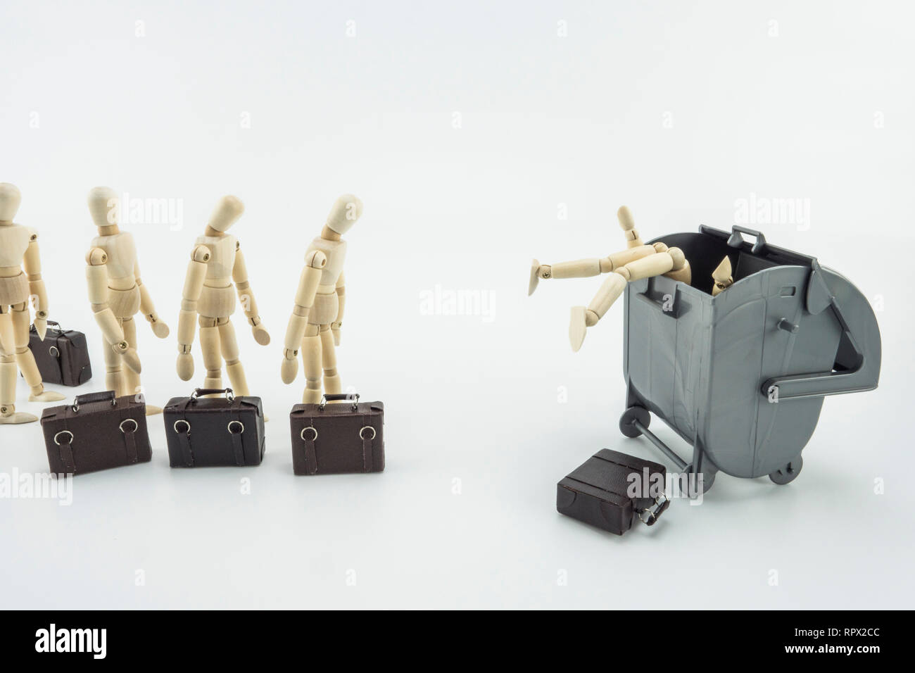 Metaphorischen Szene, Führungskräfte werfen zu einem Mülleimer, isolierte Puppen aus Holz auf weißem Hintergrund, horizontale Zusammensetzung Stockfoto