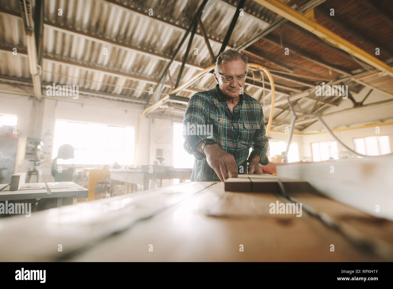 Senior Zimmermann arbeitet auf der Maschine mit der Herstellung von Produkten aus Holz. Tischler schneidet das Holz verschiedener Konfigurationen auf der Kreissäge mac Stockfoto