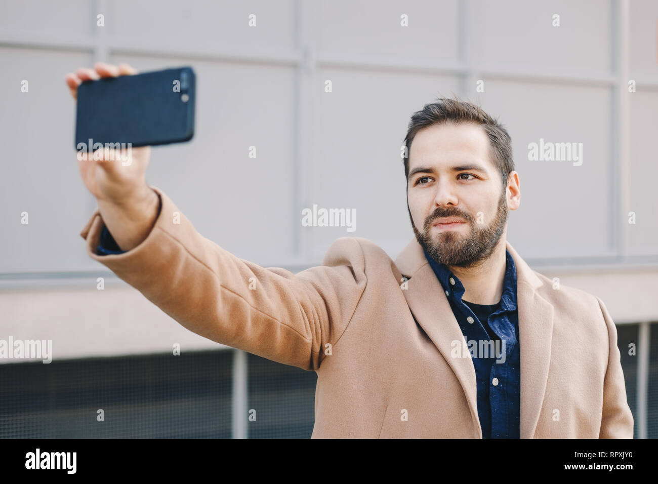 Close-up Portrait von attraktiven und modernen jungen Mann eine selfie mit seinem Handy, das Tragen modischer Kleidung und posieren für Freunde auf Soci Stockfoto