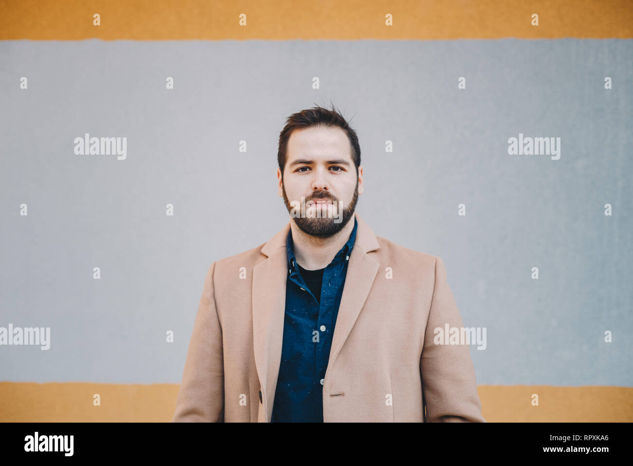 Close-up Portrait von attraktiven, modernen jungen Mann posiert und auf die Kamera, das Tragen modischer Kleidung vor einem bunten Hintergrund. Stockfoto