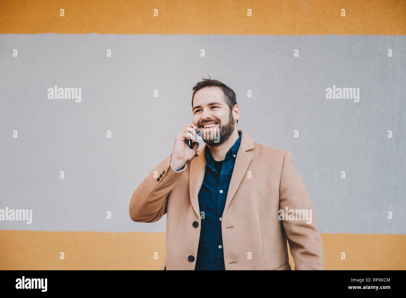 Portrait von attraktiven, modernen jungen Mann in einem Handy Gespräch, in der modischen Kleidung vor einem bunten Hintergrund posiert. Spac Stockfoto