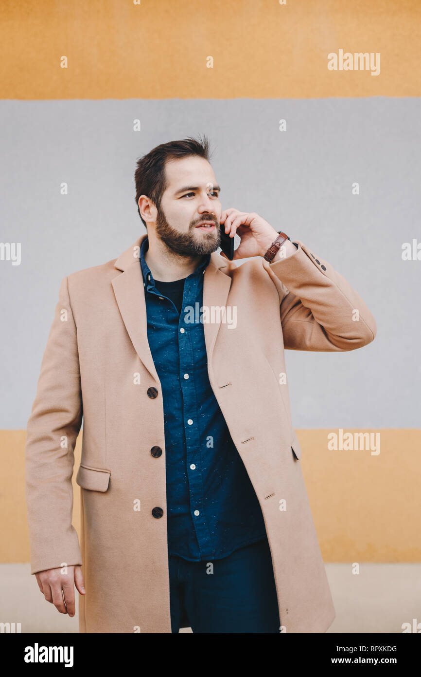 Portrait von attraktiven, modernen jungen Mann in einem Handy Gespräch, in der modischen Kleidung vor einem bunten Hintergrund posiert. Spac Stockfoto