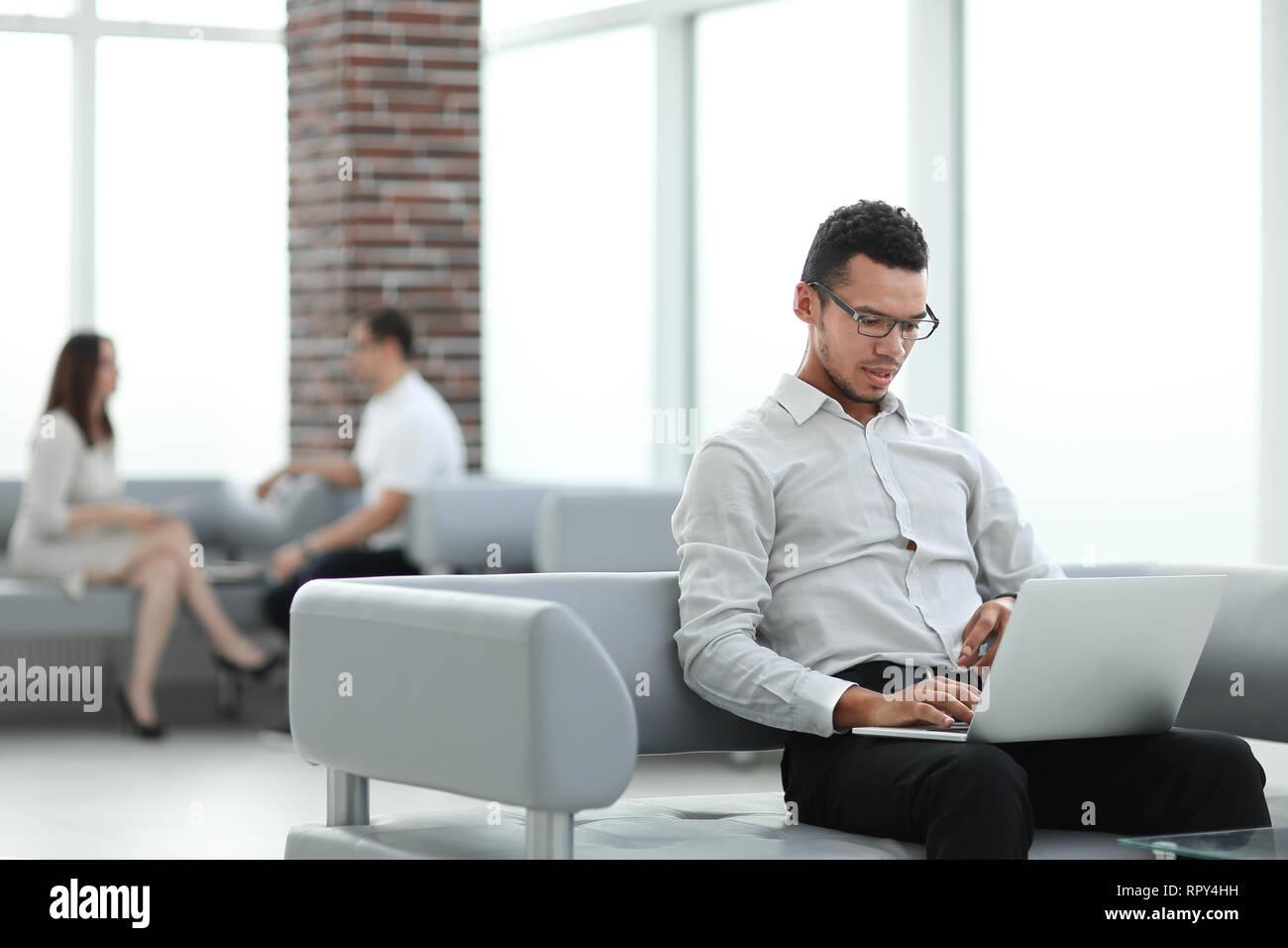 Junge Mann arbeitet auf einem Laptop in der Lobby Stockfoto