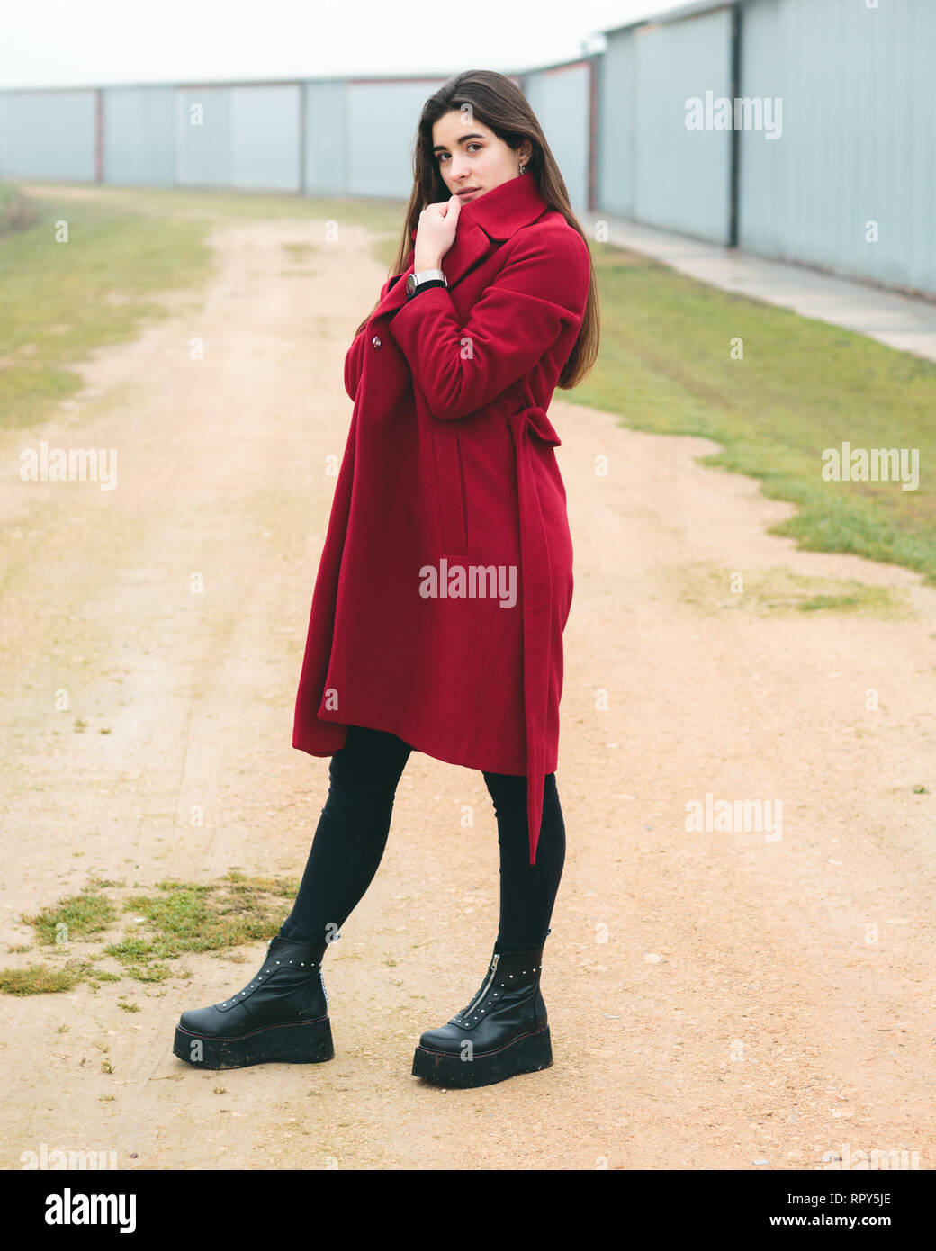 Mode Frau Porträt der jungen hübschen Mädchen posiert in einer ländlichen Szene in Europa. Winter und Frühling Mode, trägt eine rote Jacke. Stockfoto