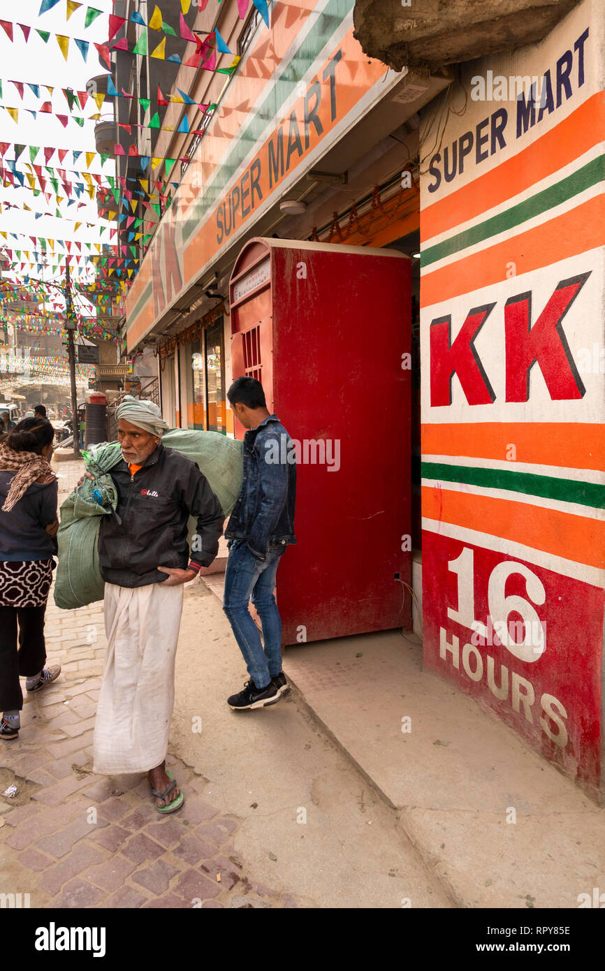 Nepal, Kathmandu, Thamel, Swayambhu Marg, Mann vorbei im britischen Stil rote Telefonzelle außerhalb KK Supermarkt Stockfoto