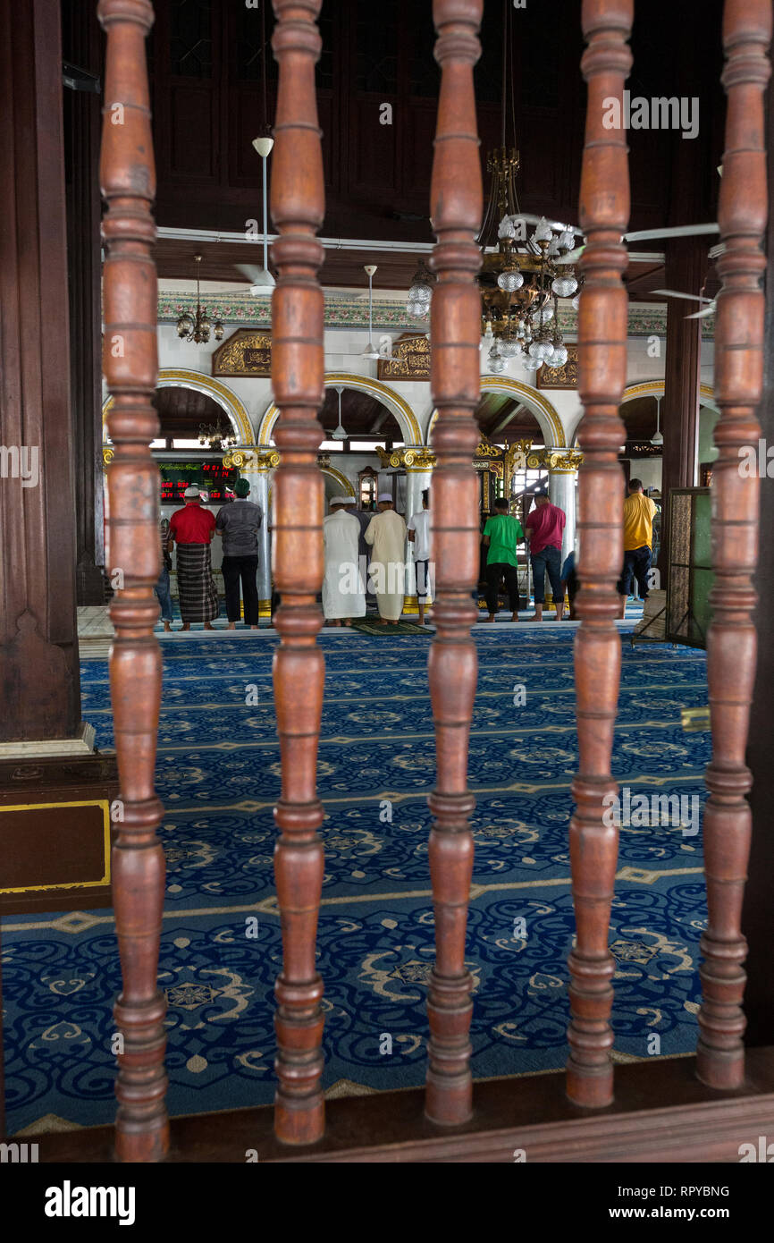 Malaysia Spindeln im Fenster von Kampung Kling Moschee Masjid Kampung Kling, Melaka, Malaysia. Männer im Gebet nach innen. Stockfoto