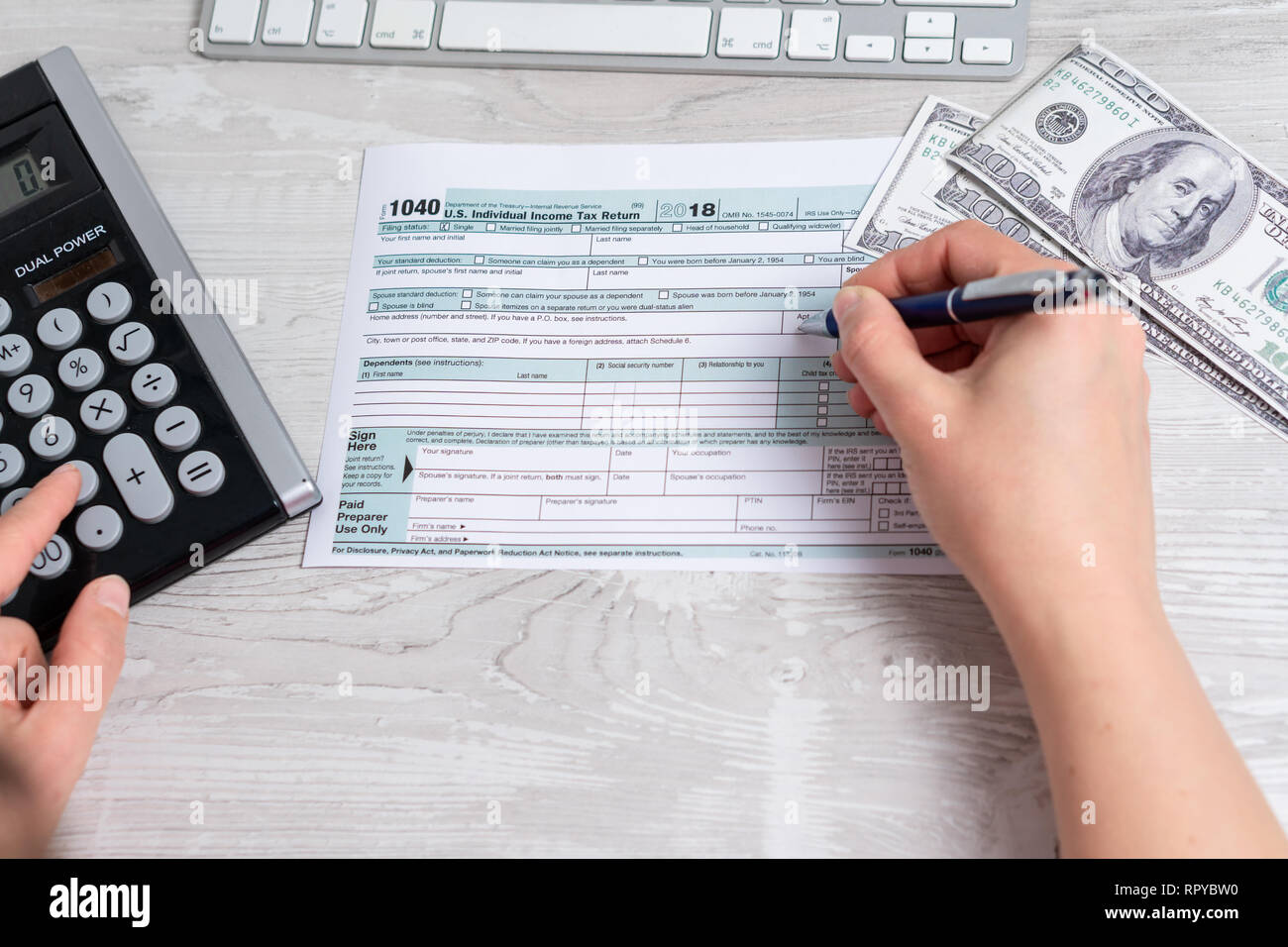 Sicht Foto von Frau Berechnung und füllen uns Steuerformular neben Computer Tastatur, Dollar, Rechnungen und Steuern Form 1040. 15. April 2019 Steuer Tag Stockfoto