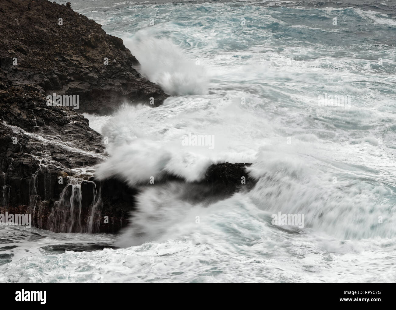 Eine Welle bricht bei stürmischem Wetter auf einem Riff vor einer felsigen Küste, Wasser Bewegung in lange Belichtung - Ort: Spanien, Kanarische Inseln, La Palma Stockfoto