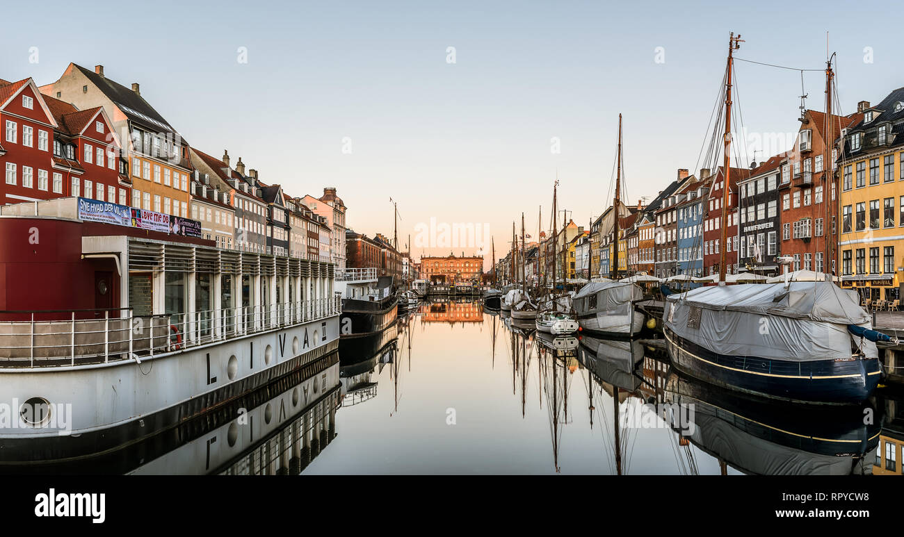 Die Sonne geht ans Licht breitet sich über das ruhige Wasser und die Boote im Hafen Nyhavn in Kopenhagen, 16. Februar 2019 Stockfoto