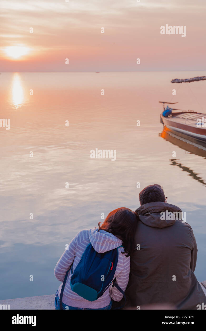 Valencia, Spanien - 23. Februar 2019: Frau liegend auf die Schulter ihres Freundes und beobachten den Sonnenuntergang. Paar am See. Stockfoto