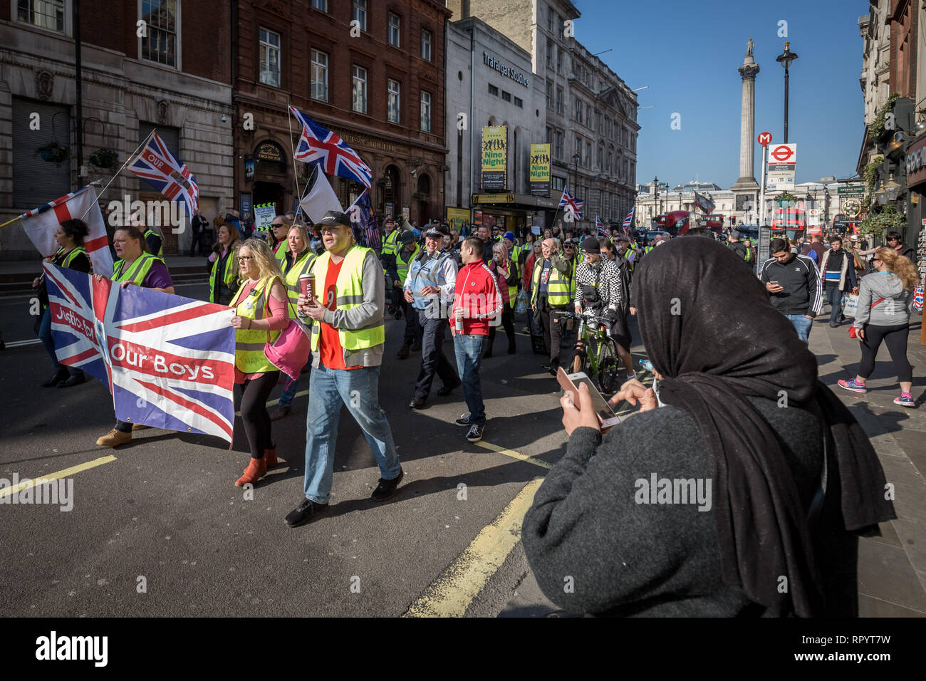 London, Großbritannien. 23. Februar, 2019. Eine muslimische Frau überprüft Ihr Telefon als Demonstranten märz hinunter Whitehall. Pro-Brexit Demonstranten, die sich selbst die "Bewegung blockieren Straßen Gelb UK' und Verkehr während Protest marschieren durch Westminster. Die rechten Nationalisten kurz mit Polizei und wütenden Fahrer kollidierte während aggressiv anspruchsvolle Großbritannien der EU ohne einen Ausgang behandeln lassen. Credit: Guy Corbishley/Alamy leben Nachrichten Stockfoto