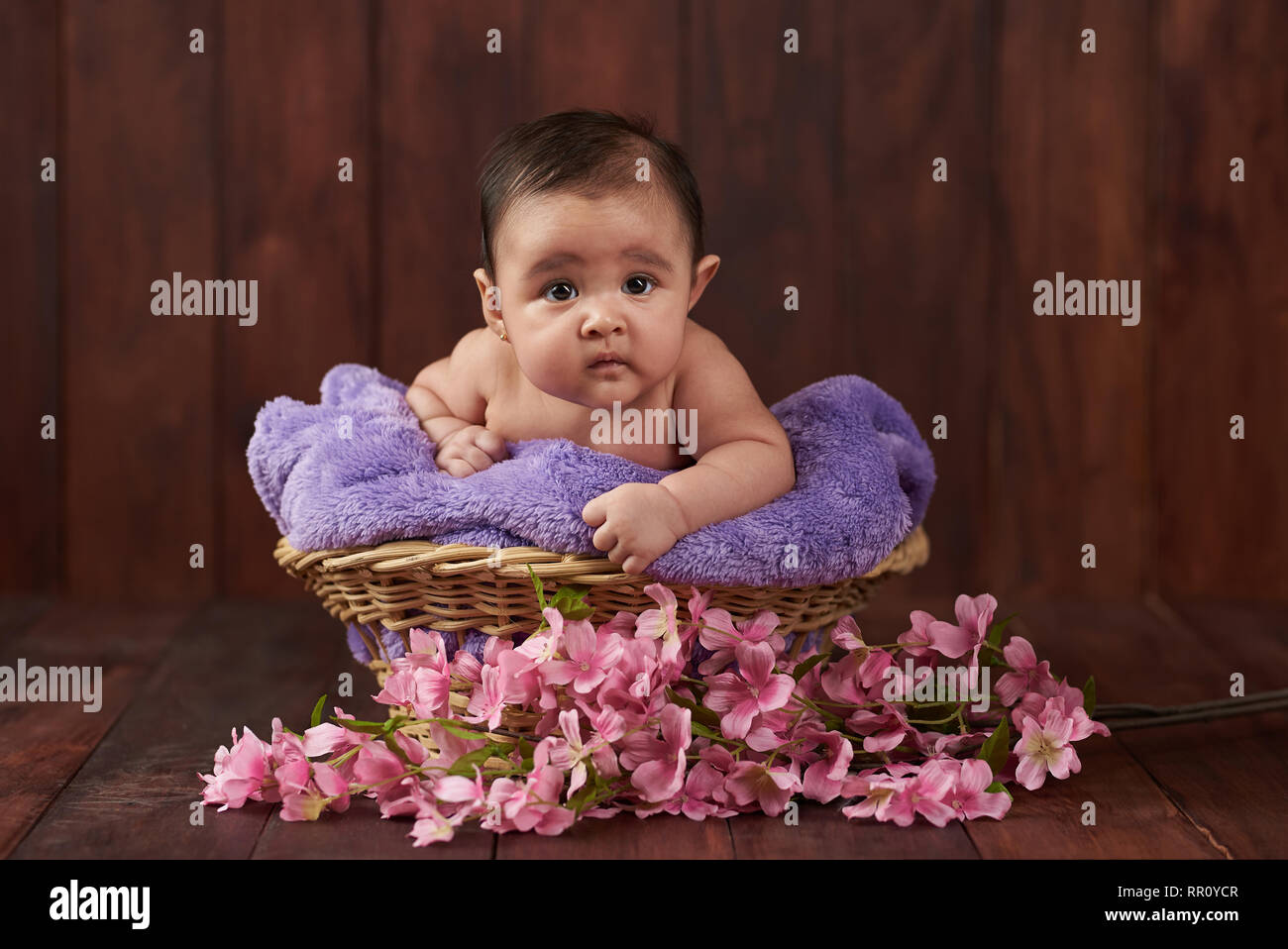 Portrait von niedlichen kleinen Baby im Korb mit Blumen Stockfoto
