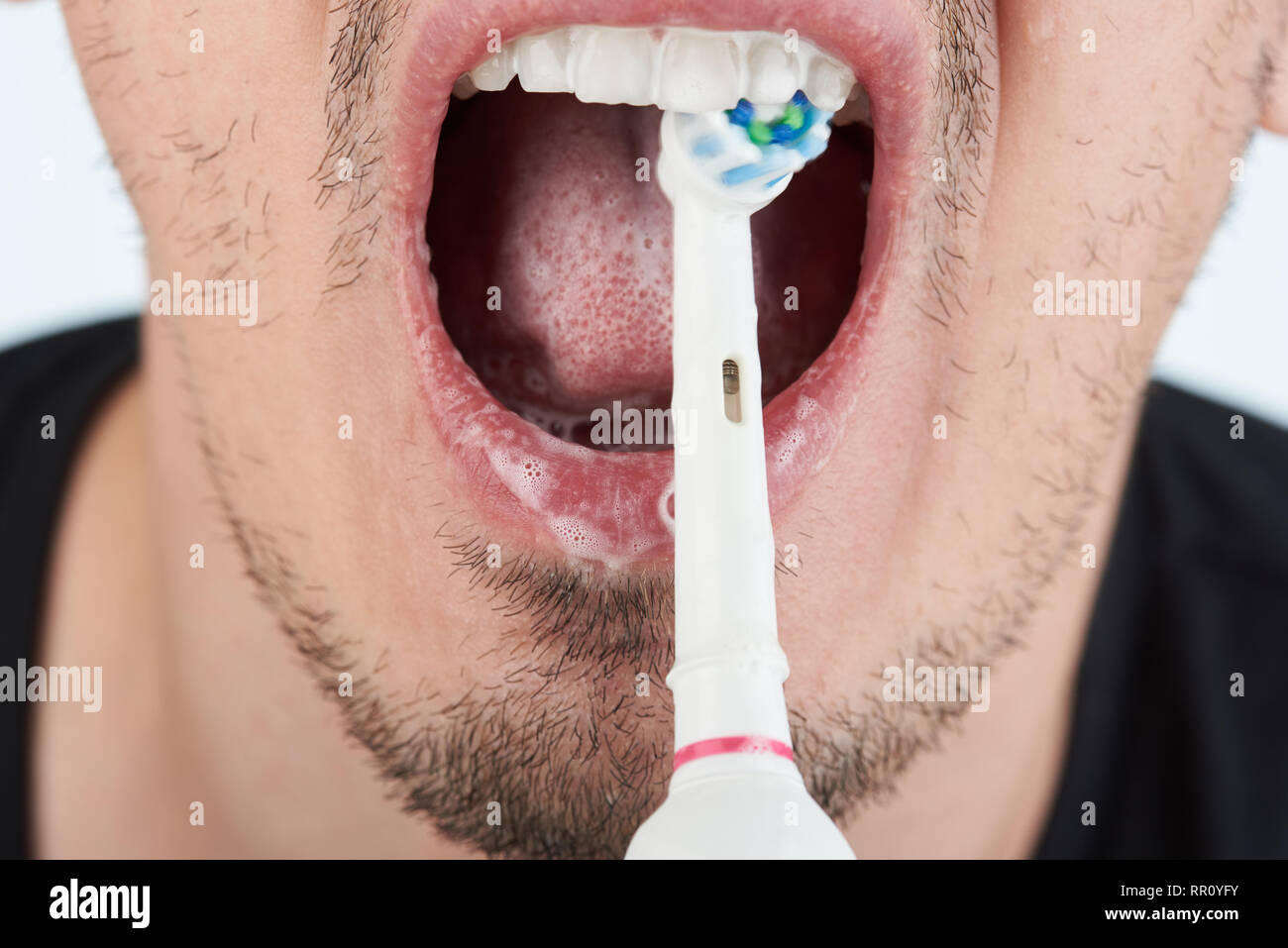 Reinigung der Zähne mit Zahnpasta und elektronische Zahnbürste Stockfoto