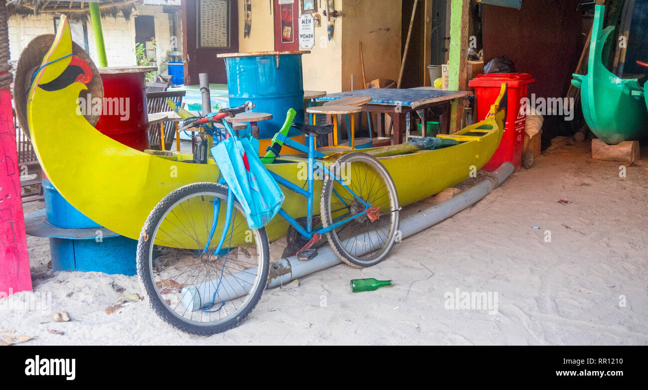 Eine bicycled lehnte sich gegen ein jukung traditionellen hölzernen Angeln Kanu in einem boatshed, Jimbaran Bay Bali Indonesien. Stockfoto