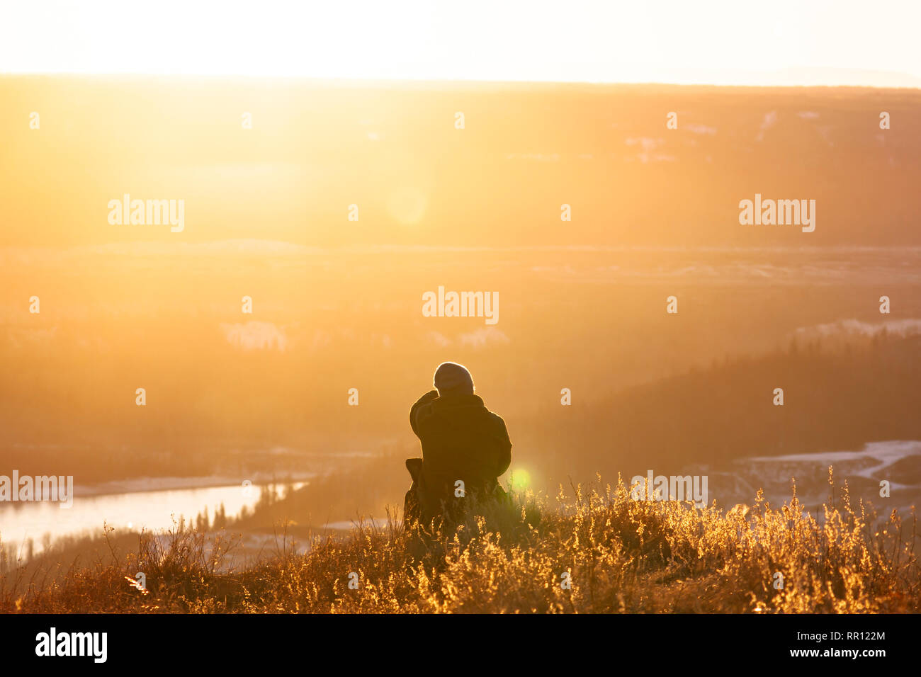 Das Sitzen auf einem Hügel bei Sonnenuntergang wandern Sie suchen Stockfoto