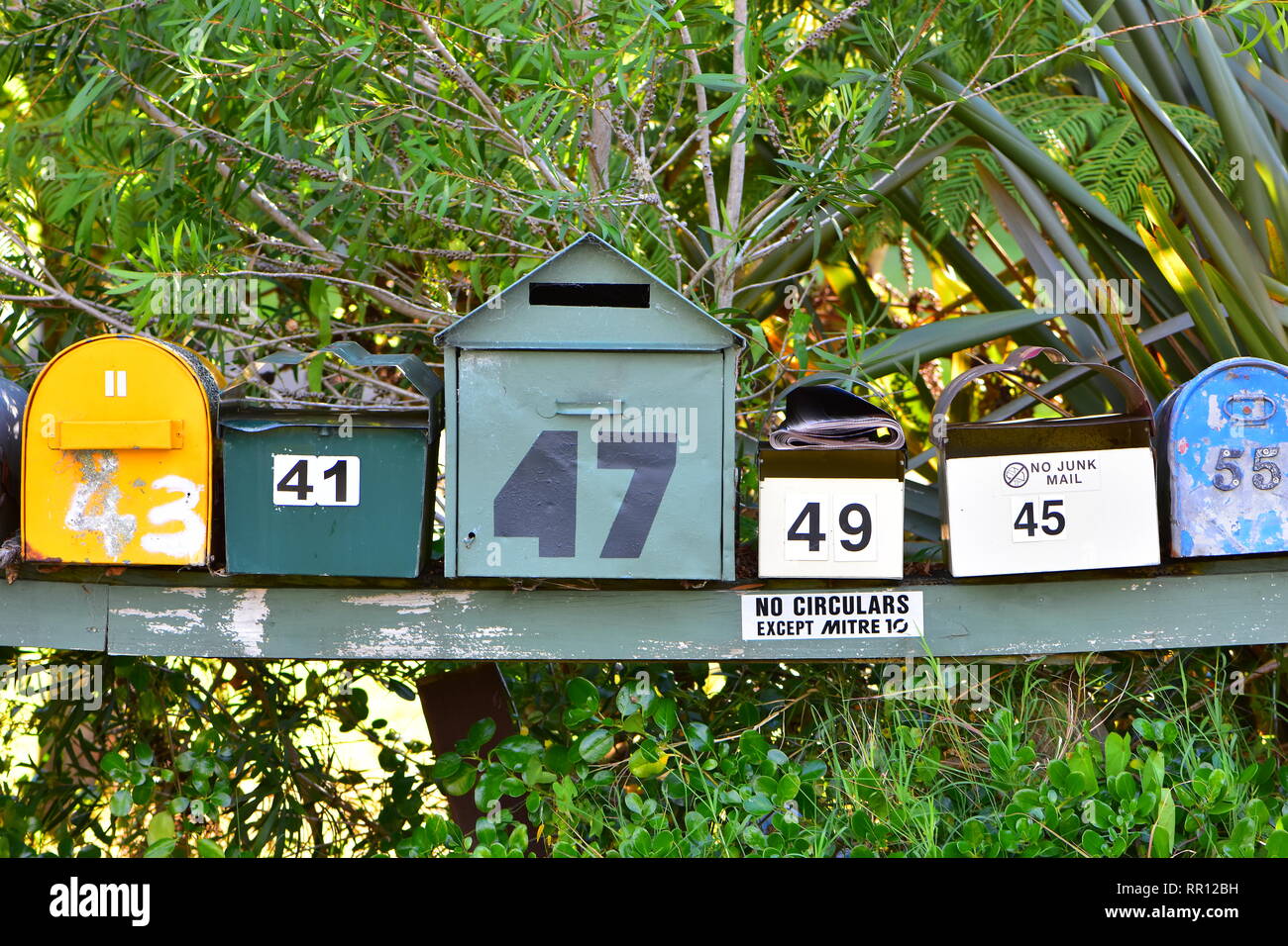 Bunte Mailboxen in verschiedenen Größen und Stile leicht gebogen Holzregal mit Farbe. Stockfoto