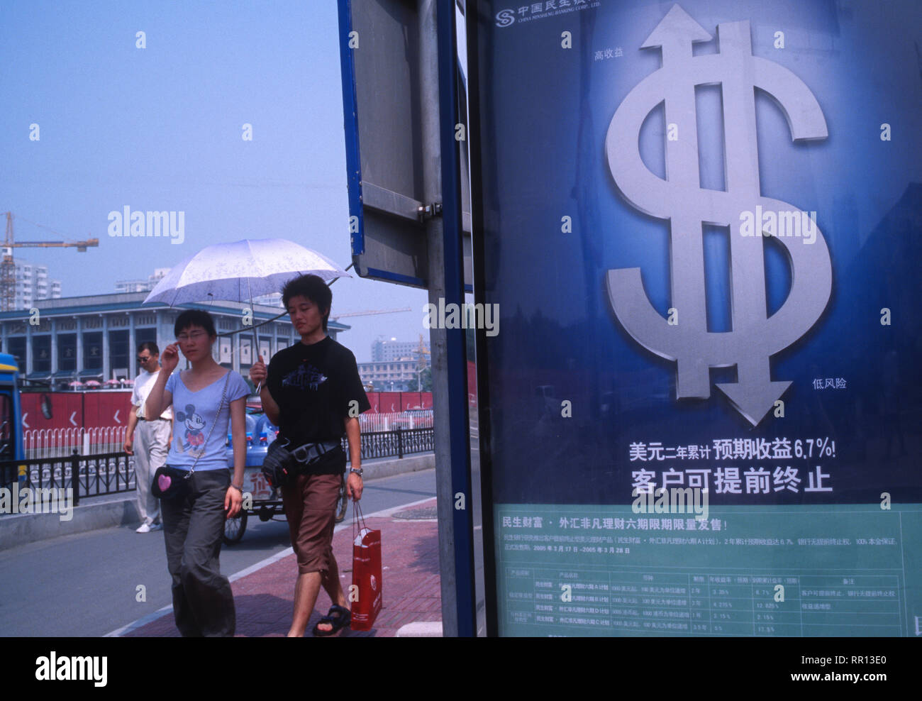 Chinesische Fußgänger vorbei an einer Anschlagtafel der Dollar Investitionen in Peking, China. 2005 Stockfoto