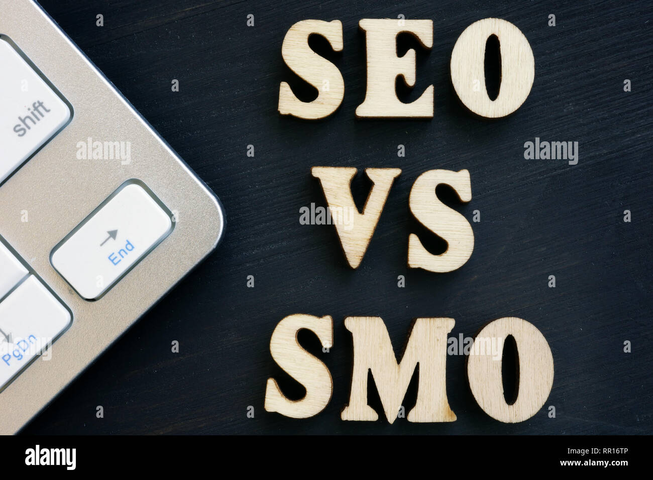 SEO vs SMO und Tastatur auf einem dunklen Schreibtisch. Stockfoto