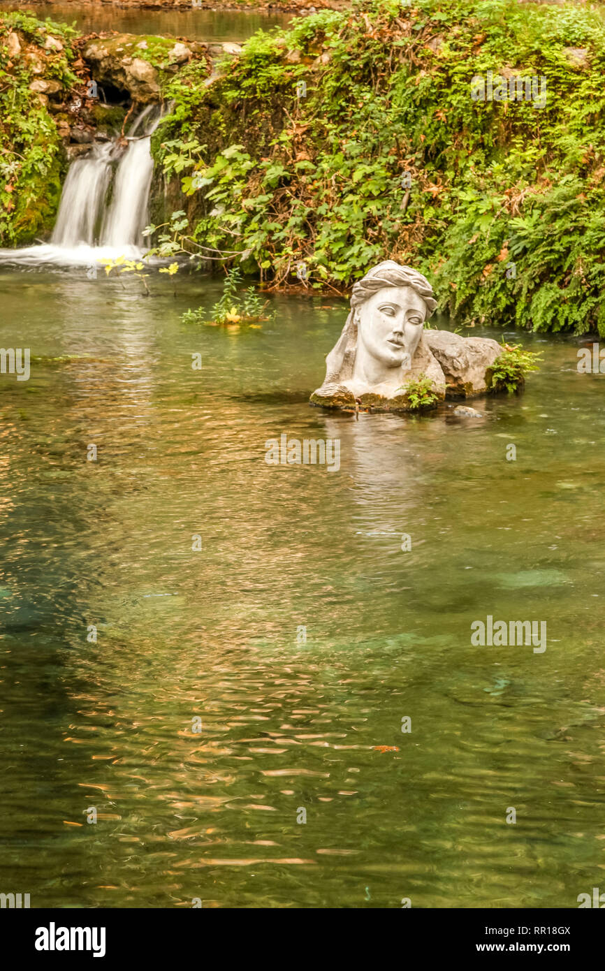 Fluss Erkyna, die eine der beiden Flüsse des weiblichen Namen in Griechenland, in der Stadt Livadeia, Zentral Griechenland. Die Büste verkörpert Göttin Erkyna. Stockfoto